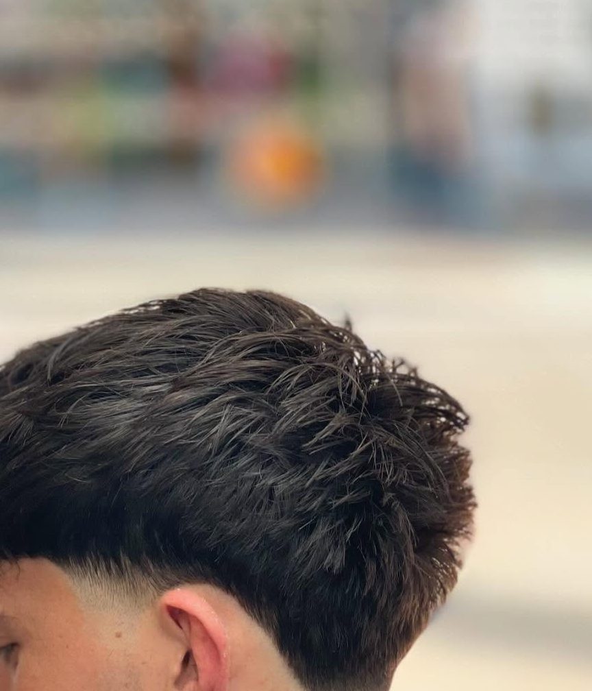 The back of a mid fade, taken short around the ear and up the back of the head into a longer top